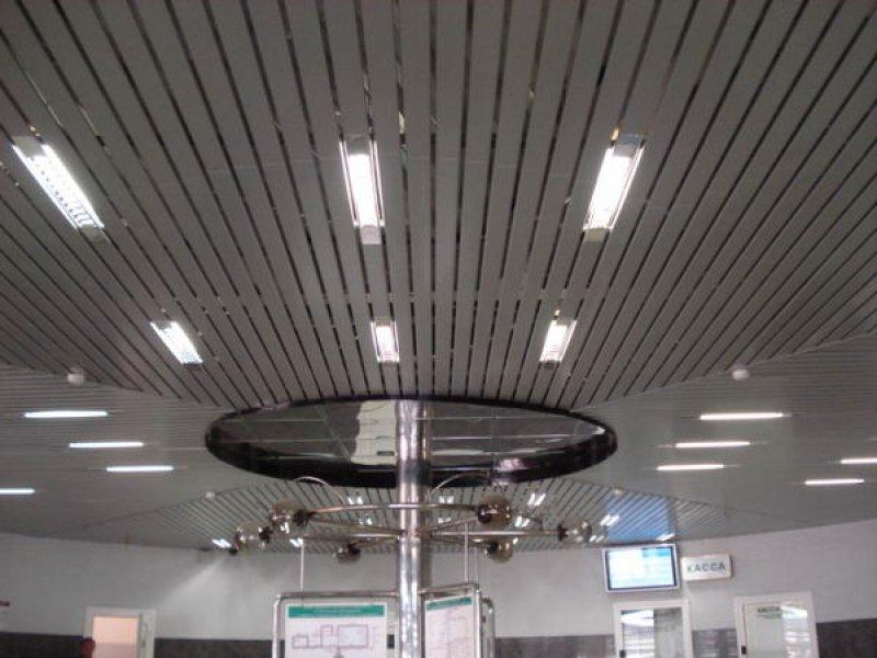 Composition of recessed lighting fixtures on a slatted ceiling.