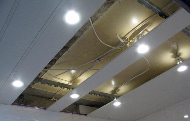 Installation of a grid ceiling with light fittings.