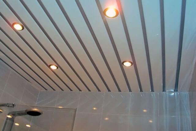 A slatted ceiling with spotlights in the bathroom.